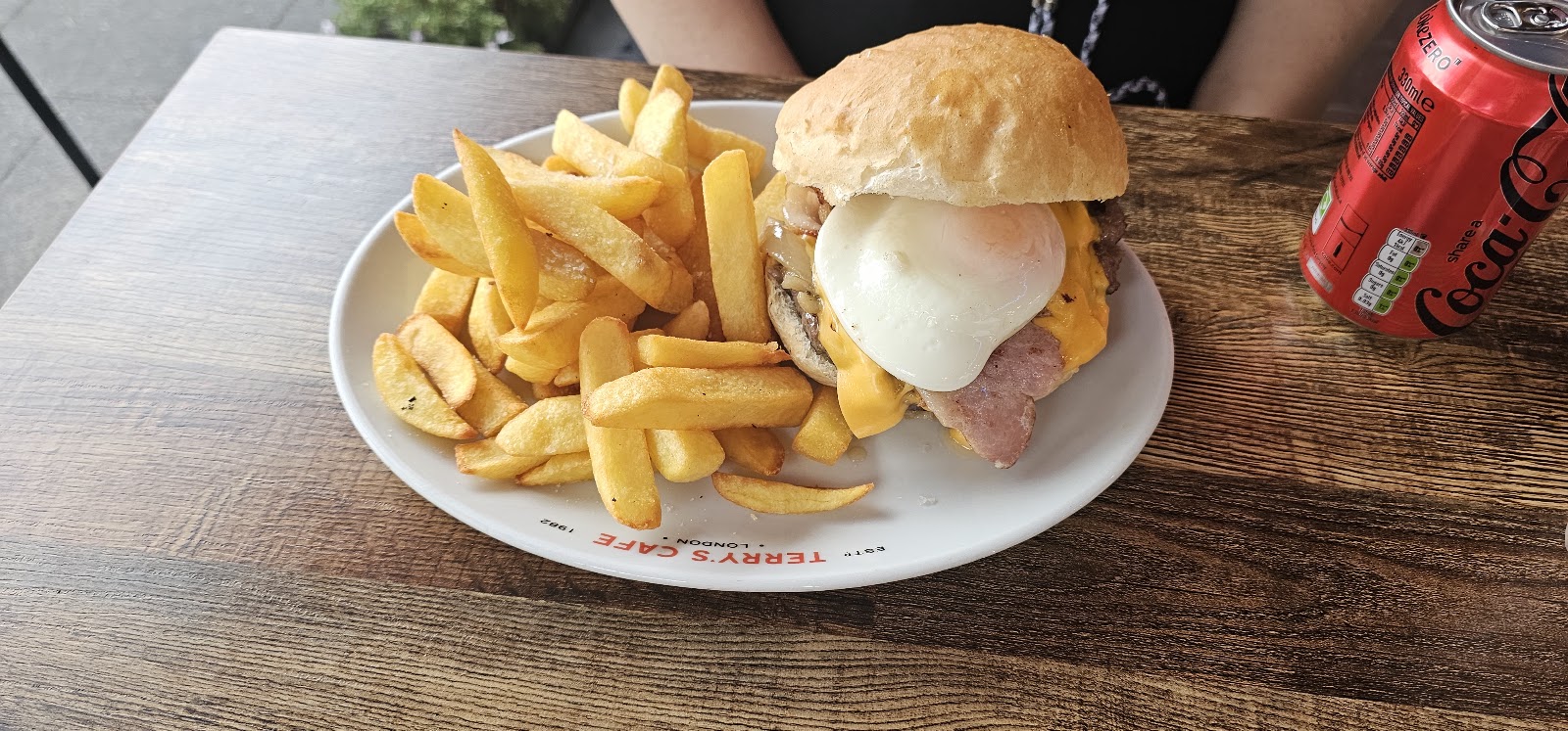 A burger topped with a fried egg, with a heap of chips